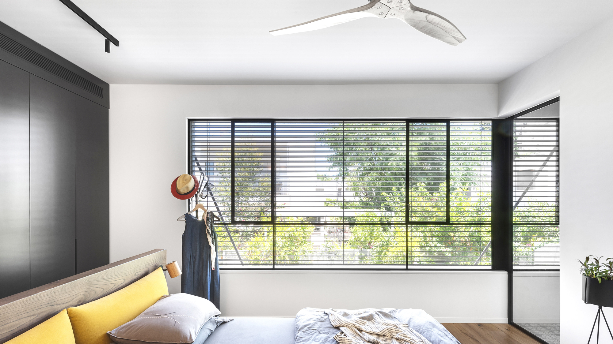 Chambre avec grande baie vitrée équipée de brise-soleil orientables filtrant la lumière naturelle