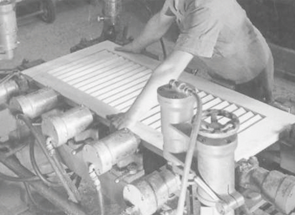Photo d’archive en noir et blanc du fondateur de Baumann Hüppe concevant un volet battant en bois.