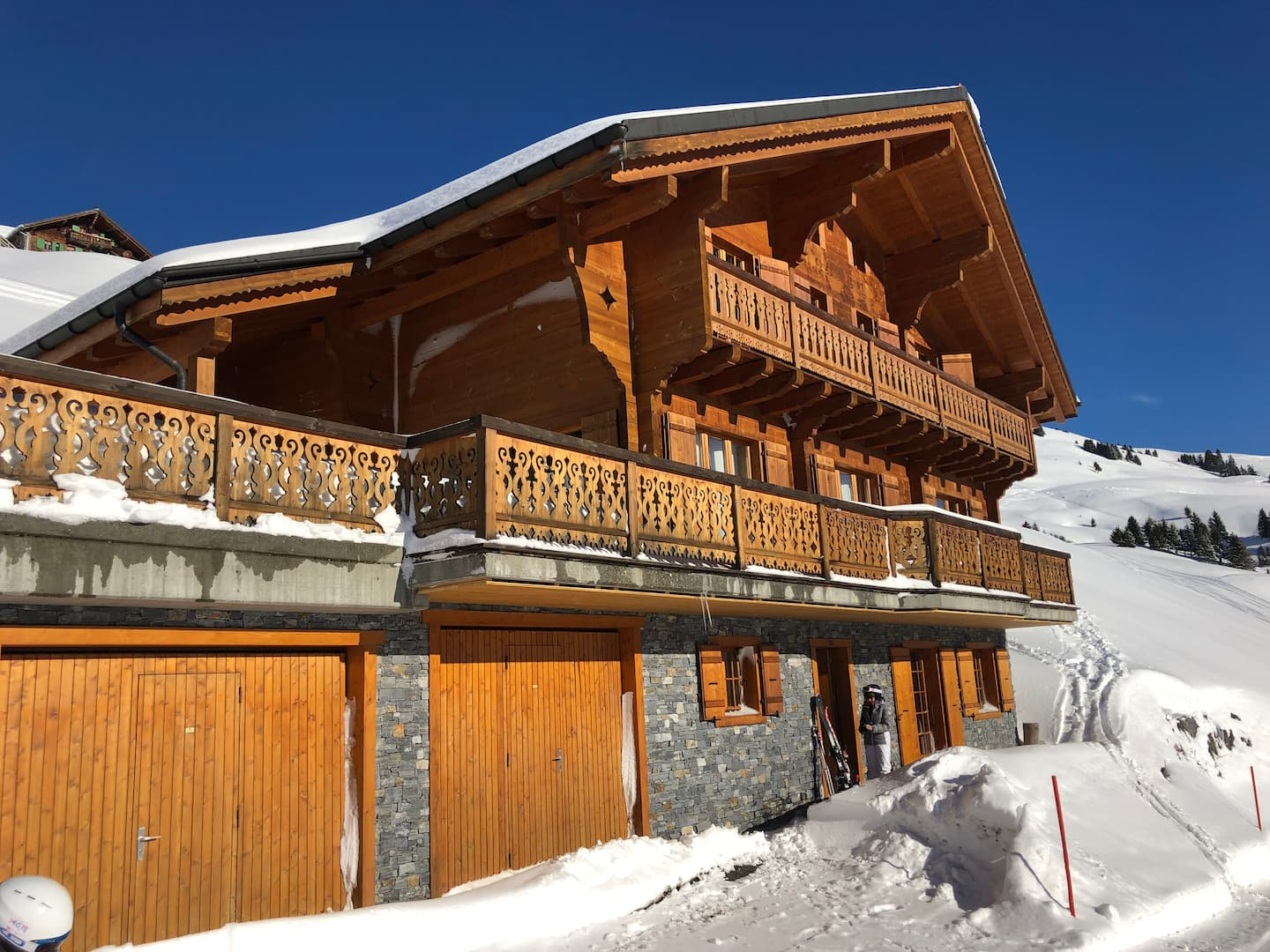 Façade en bois du Chalet Clare et ses balcons découpés sous la neige