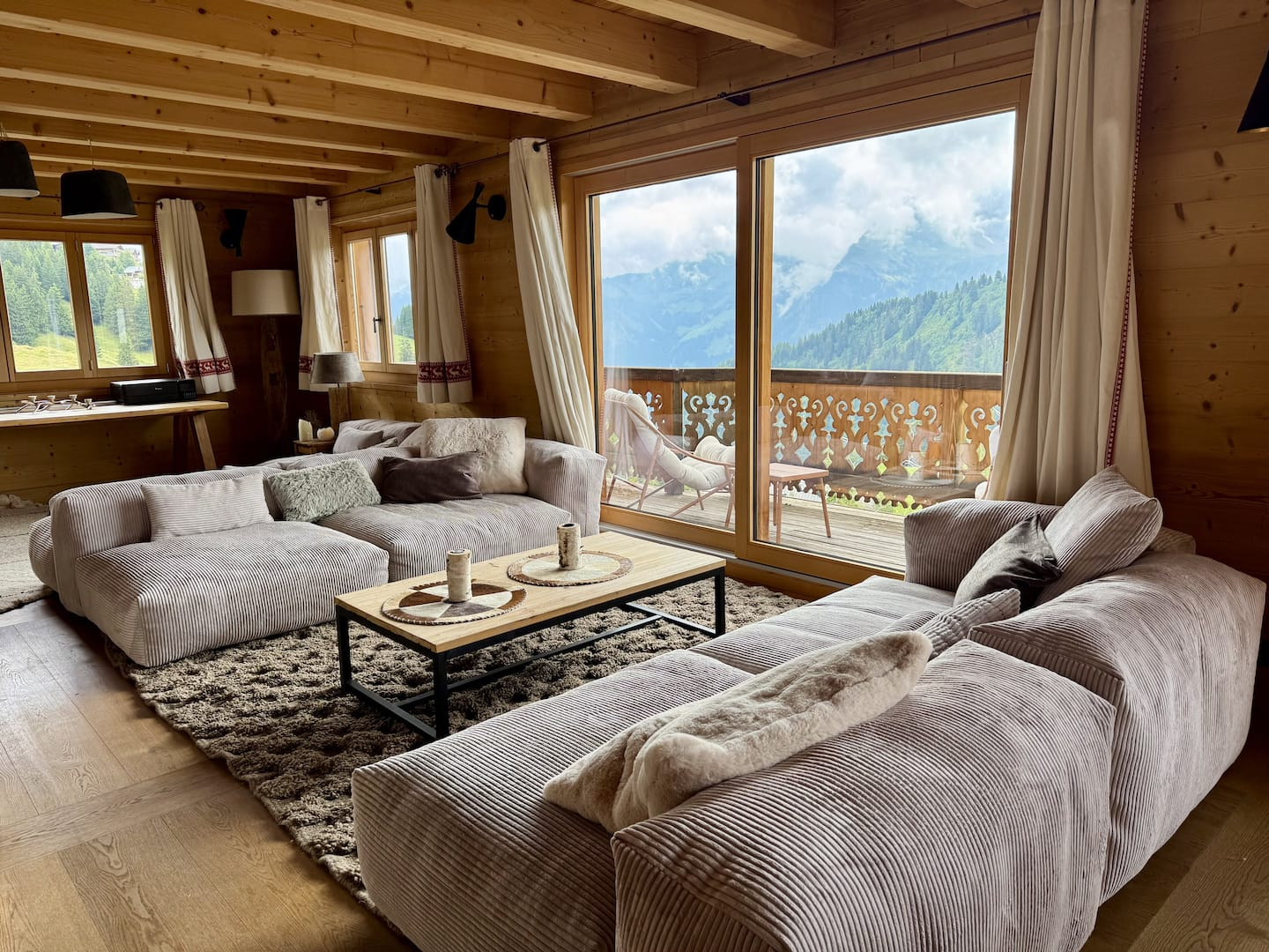 Grand salon tout en bois du Chalet Clare, baies ouvertes sur la montagne